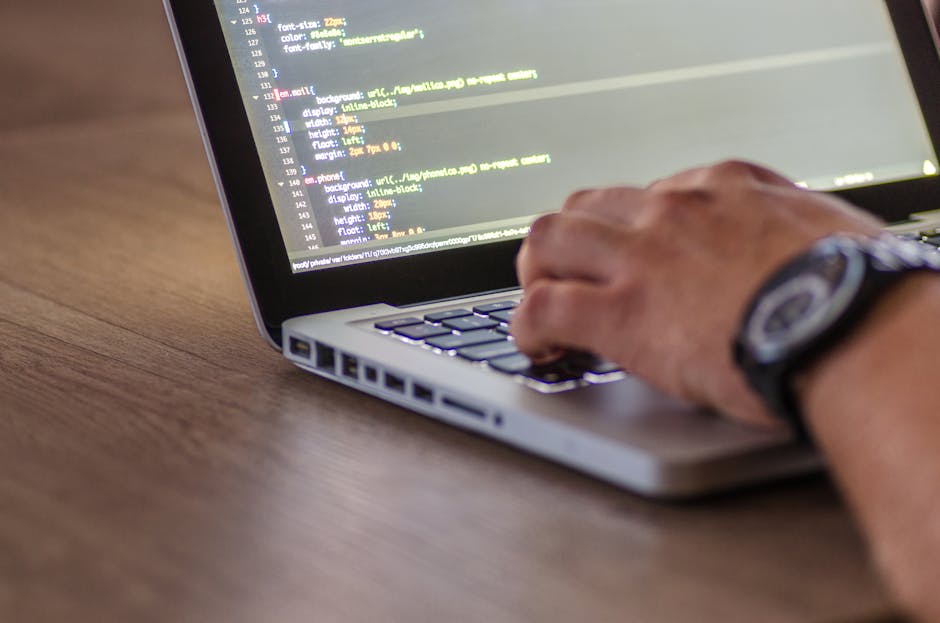 A close-up shot of a person coding on a laptop, focusing on the hands and screen
